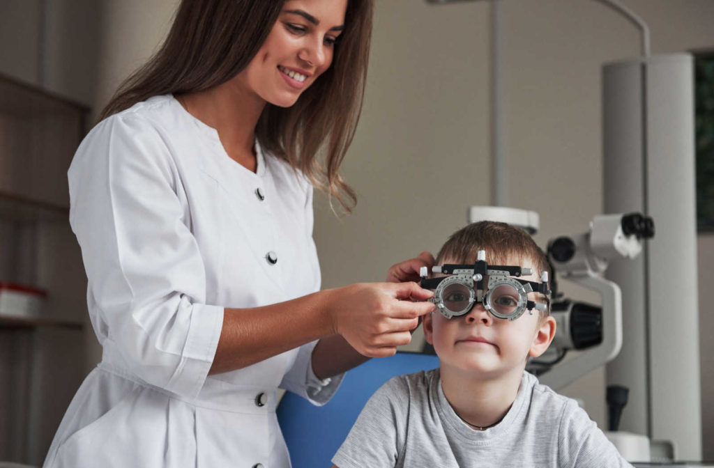 A female optometrist conducting an eye exam for a small boy.