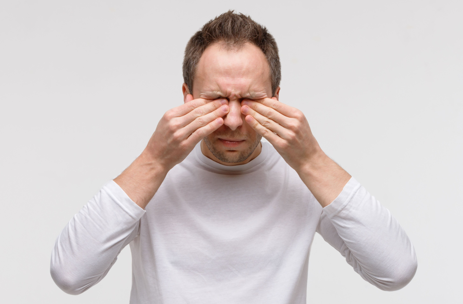 A middle-aged man rubbing his eyes with both hands