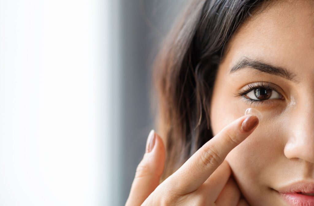 Close-up of a woman's right eye as she puts a contact lens in using her right hand